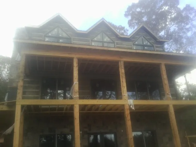 Dormers and porch framing on a large log home under construction — Roof Coating work by our crew in Fort Morgan