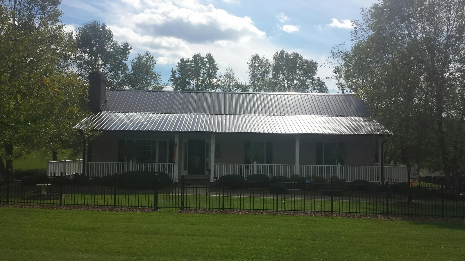Gray metal roof on a brick ranch with a full width front porch — Gutter Guard Installation work by our crew in Fort Morgan