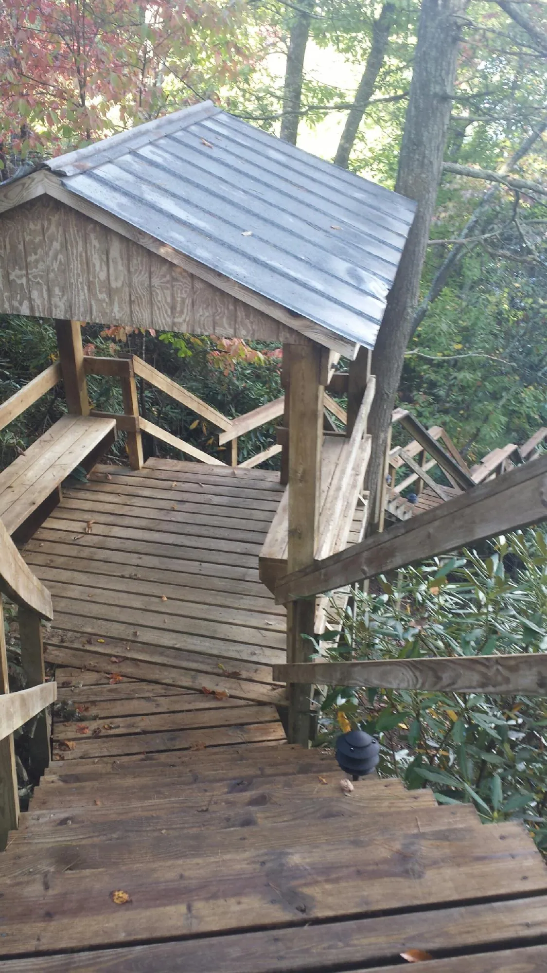 Metal roofed shelter over wooden steps on a wooded walkway — Skylight Repair & Installation work by our crew in Fort Morgan