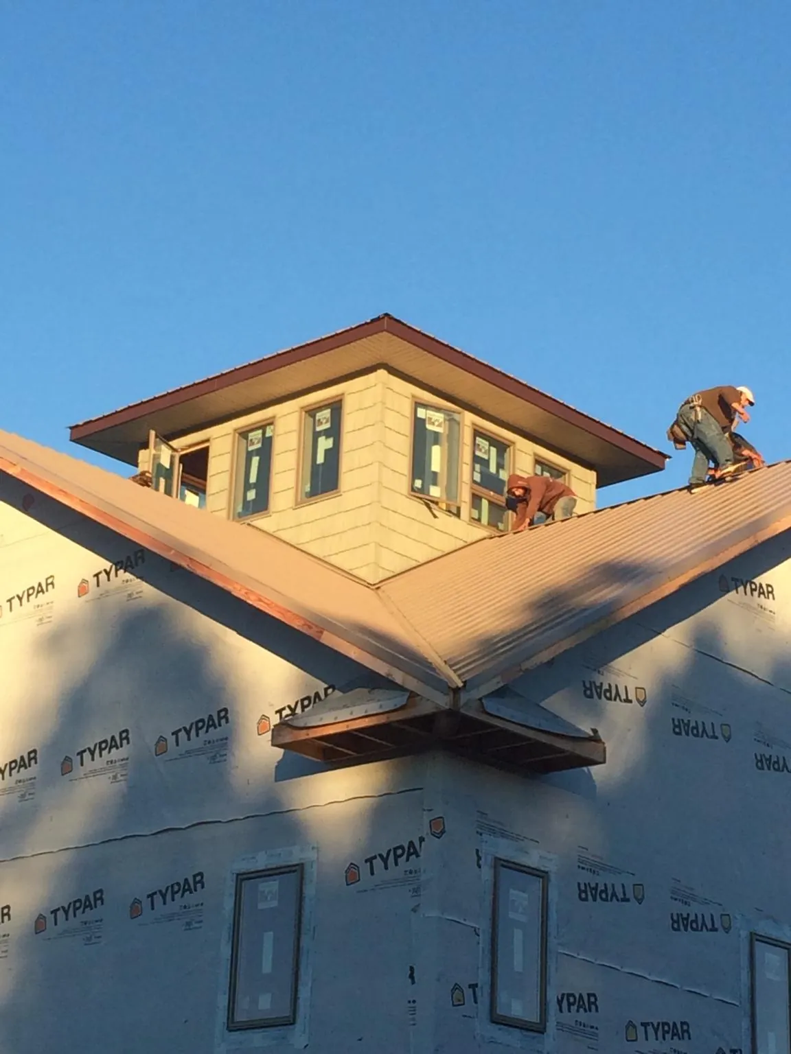 Roofers working around a rooftop cupola on a new metal roof at sunset — Roof Waterproofing in Fort Morgan by Roofing Brothers